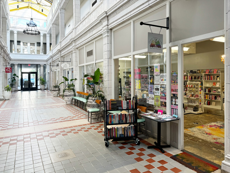 A brightly lit indoor shopping arcade with a bookstore, 