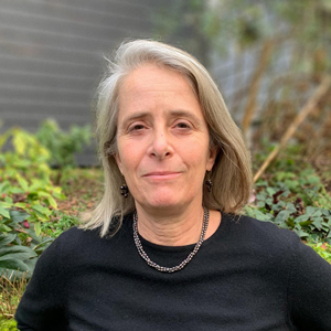 Woman with blonde hair, black shirt, and necklace