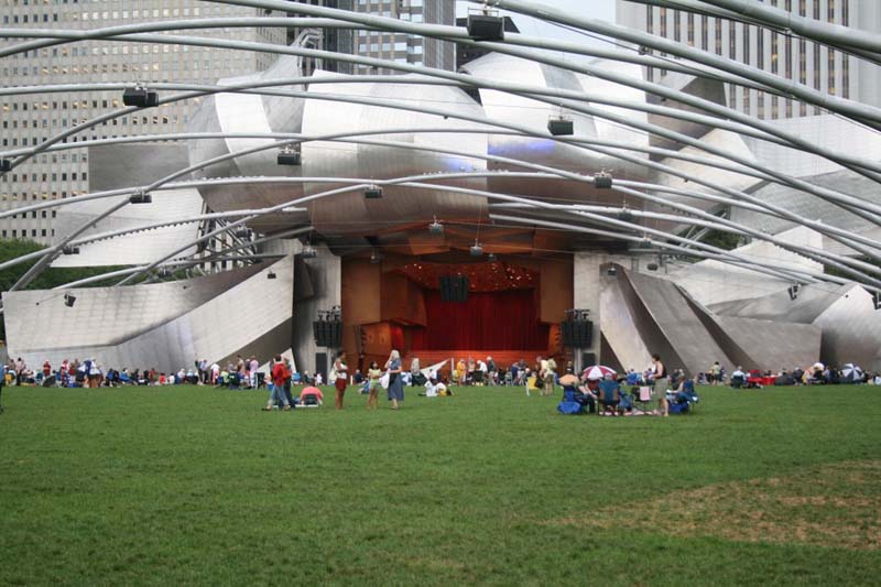 stainless steel outdoor concert venue with curved bars over grass field