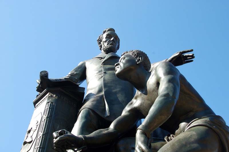 A statue of Lincoln standing next to a man rising out of bondage